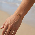 Bracelet doré animal totem dauphin porté à la plage – bijou spirituel femme en acier inoxydable inspiré du dauphin, symbole de liberté, intuition et protection marine.
