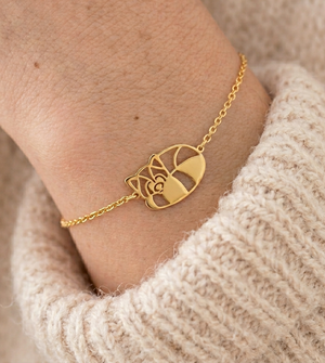 Bracelet animal totem panda roux doré porté au poignet avec un pull en maille – bijou symbolique femme inspiré du panda roux, symbole de douceur, d’équilibre, de curiosité et de sérénité.