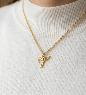 Collier colibri en acier inoxydable doré pour femme, pendentif géométrique oiseau porté sur un pull blanc en maille.