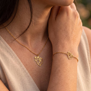 Parure de bijoux loup animal totem LIYAMI Nature : collier et bracelet dorés en acier inoxydable avec pendentifs loup géométrique, portés par une femme.