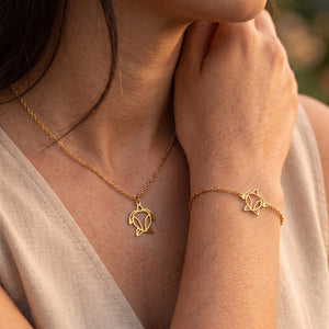 Parure de bijoux tortue animal totem LIYAMI Nature : collier et bracelet dorés en acier inoxydable avec pendentifs tortue géométrique, portés par une femme.