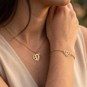 Parure de bijoux éléphant animal totem LIYAMI Nature : collier et bracelet dorés en acier inoxydable avec pendentifs éléphant géométrique, portés par une femme.